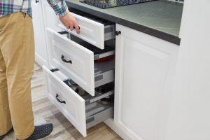 Man opening white kitchen drawers with new handles